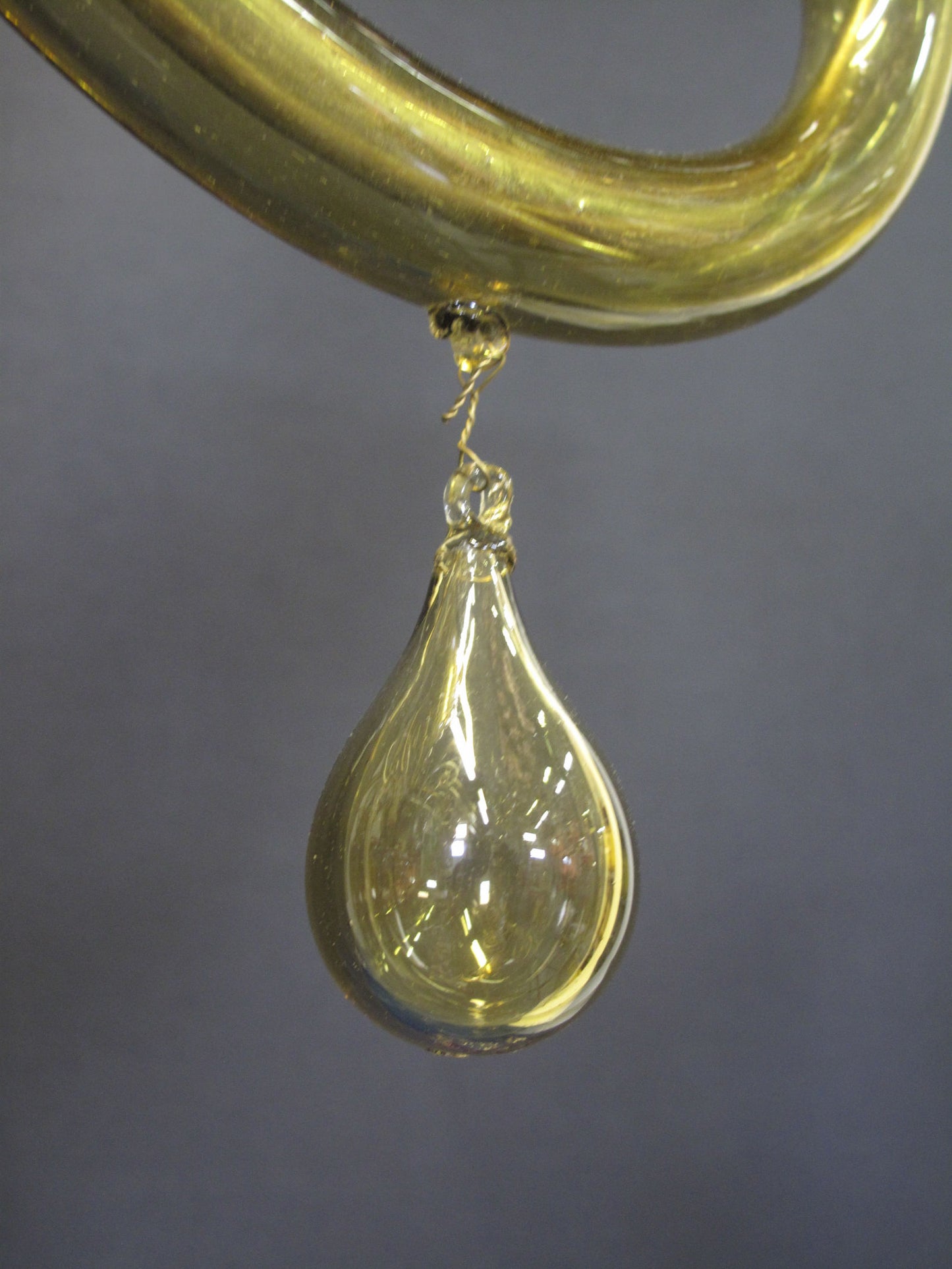 glass drop hanging from middle of arm