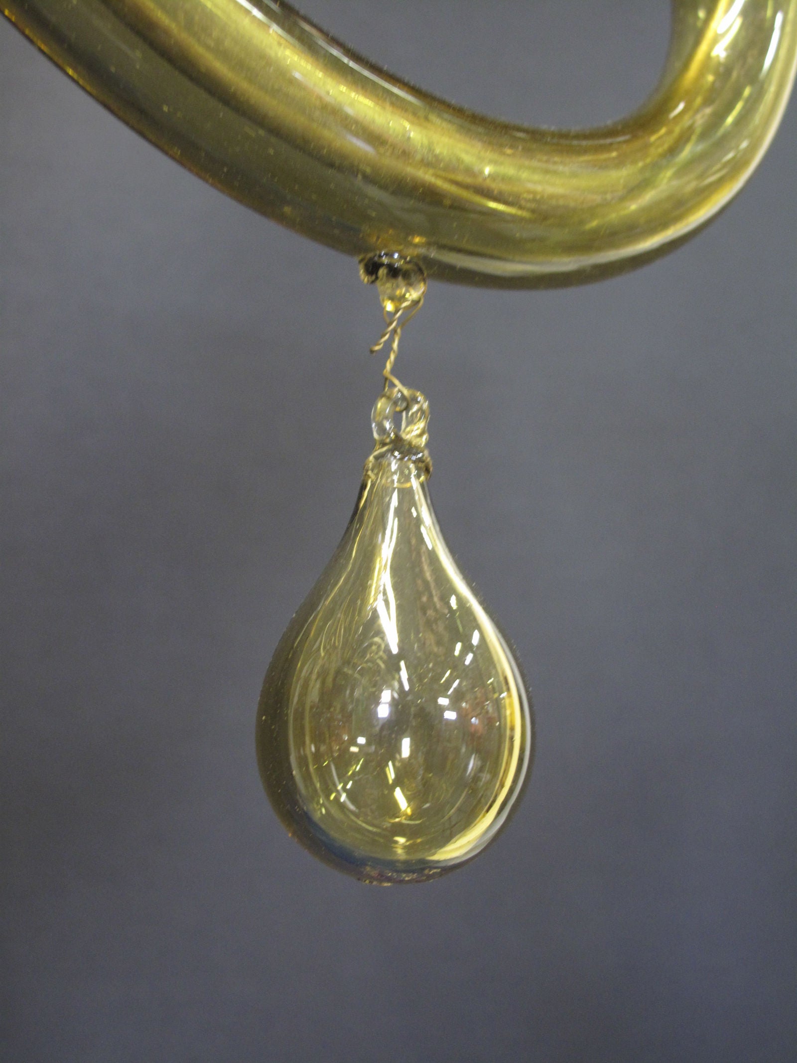 glass drop hanging from middle of arm