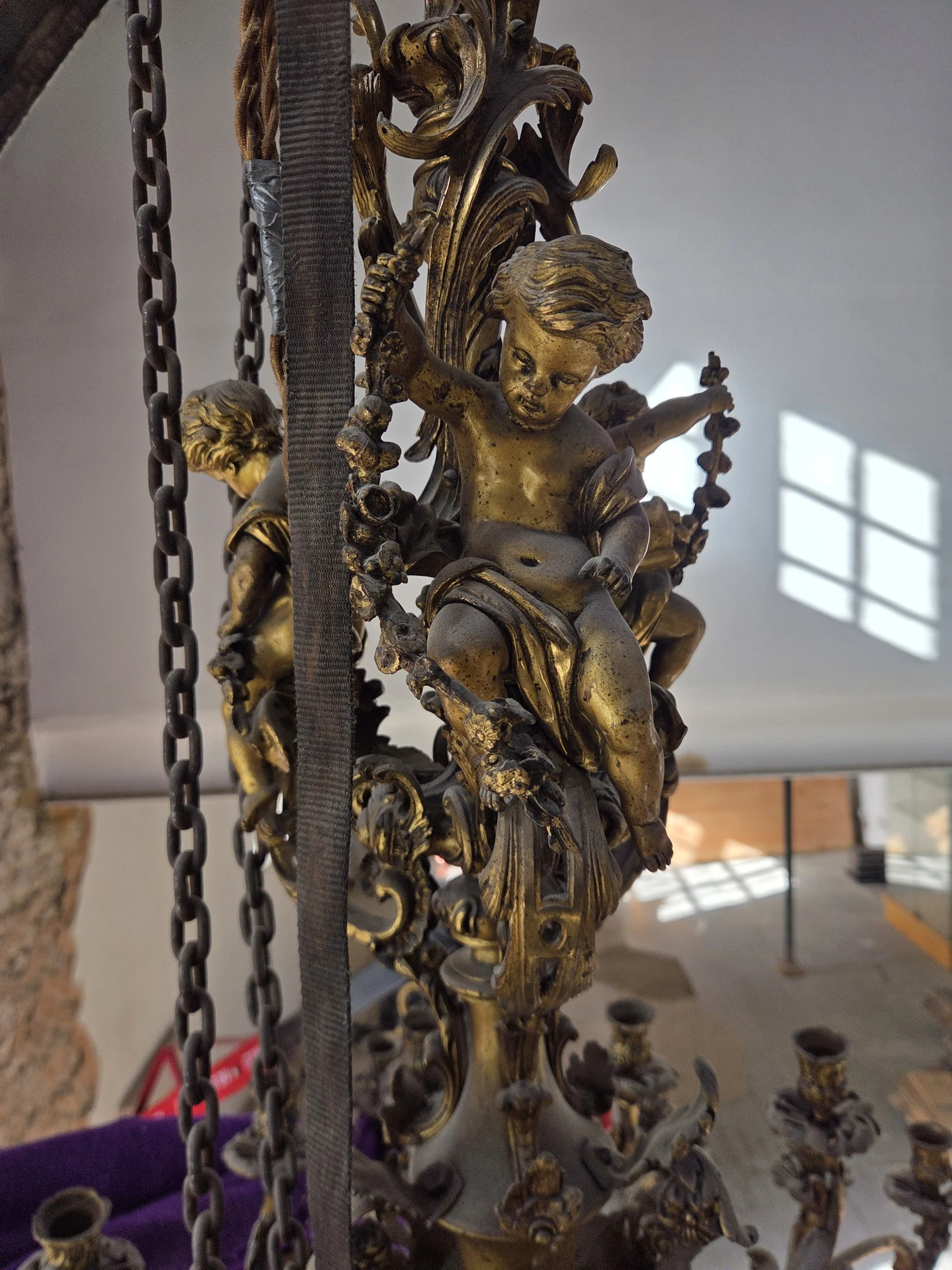 Sculpted gilt figures and scrolling ornament on the central stem of the Rococo chandelier.