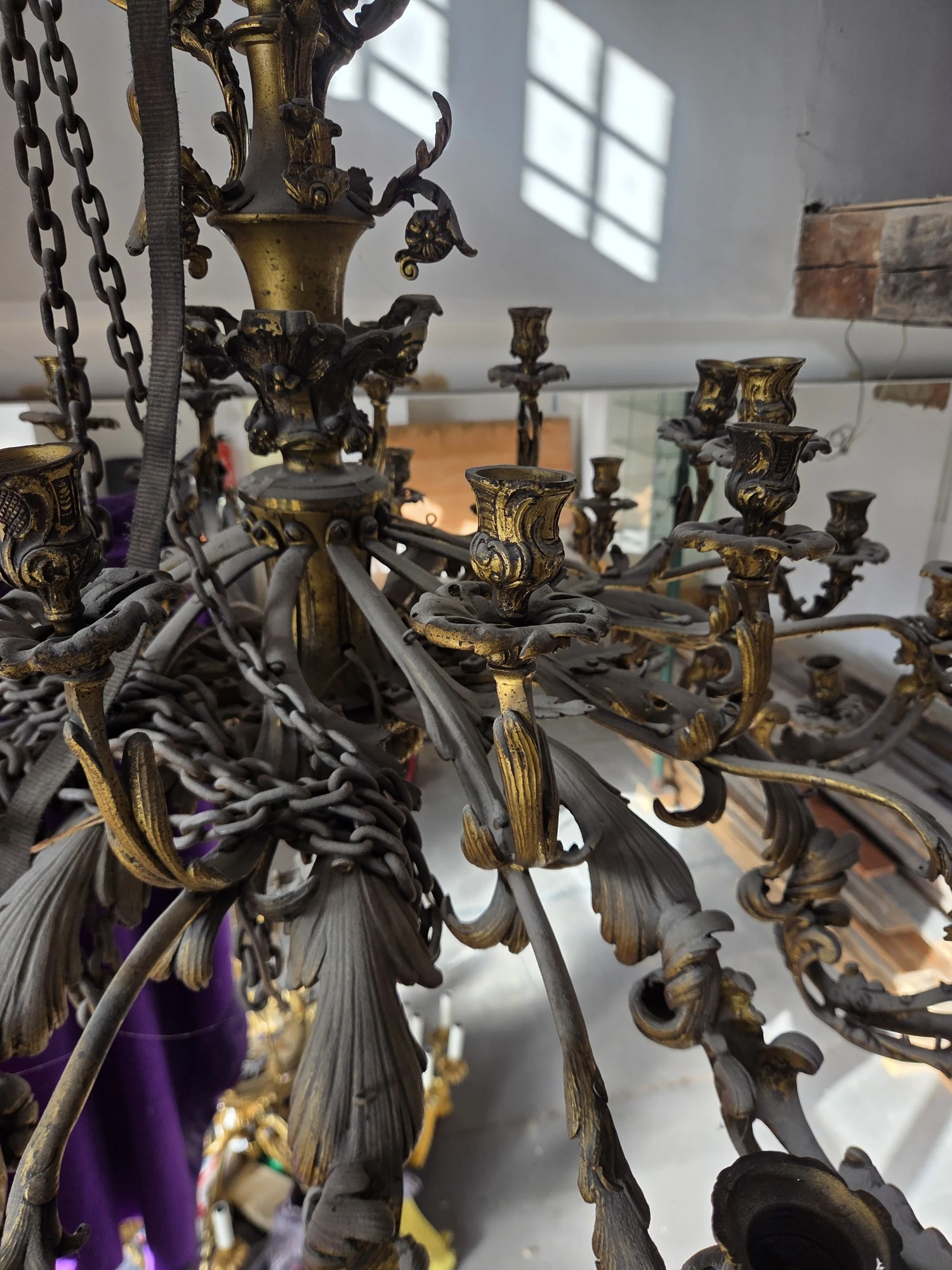 Close-up of the chandelier's scrolling Rococo-style arms, leaf ornament and candle holders.