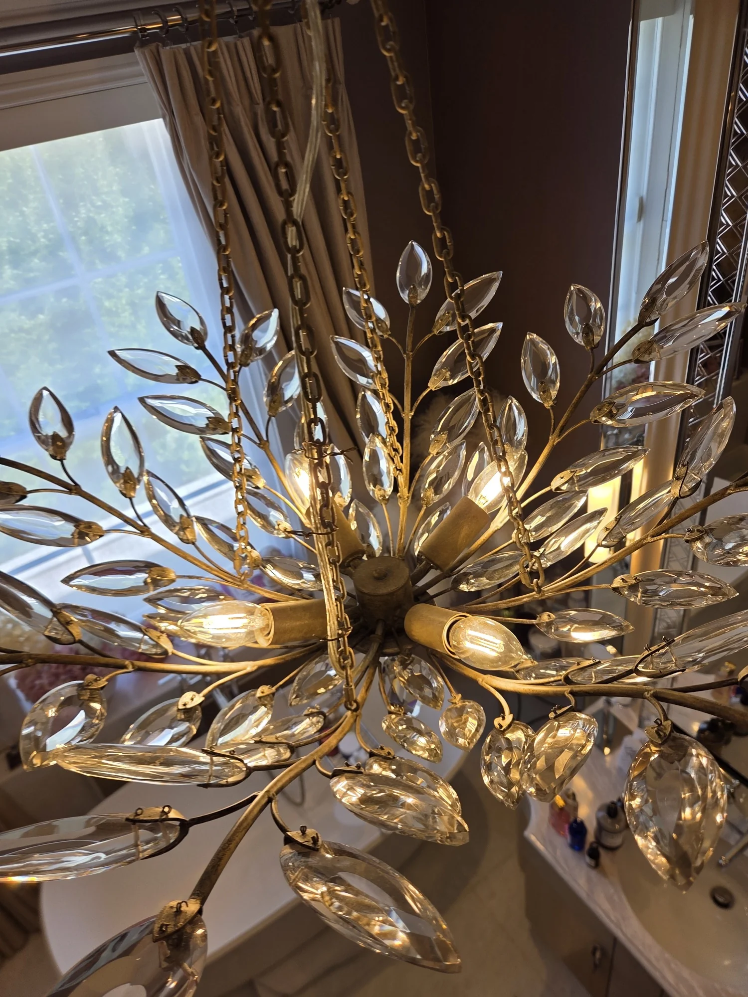 Close view from below of the central metal framework and faceted glass leaves of a chandelier in The Boltons.