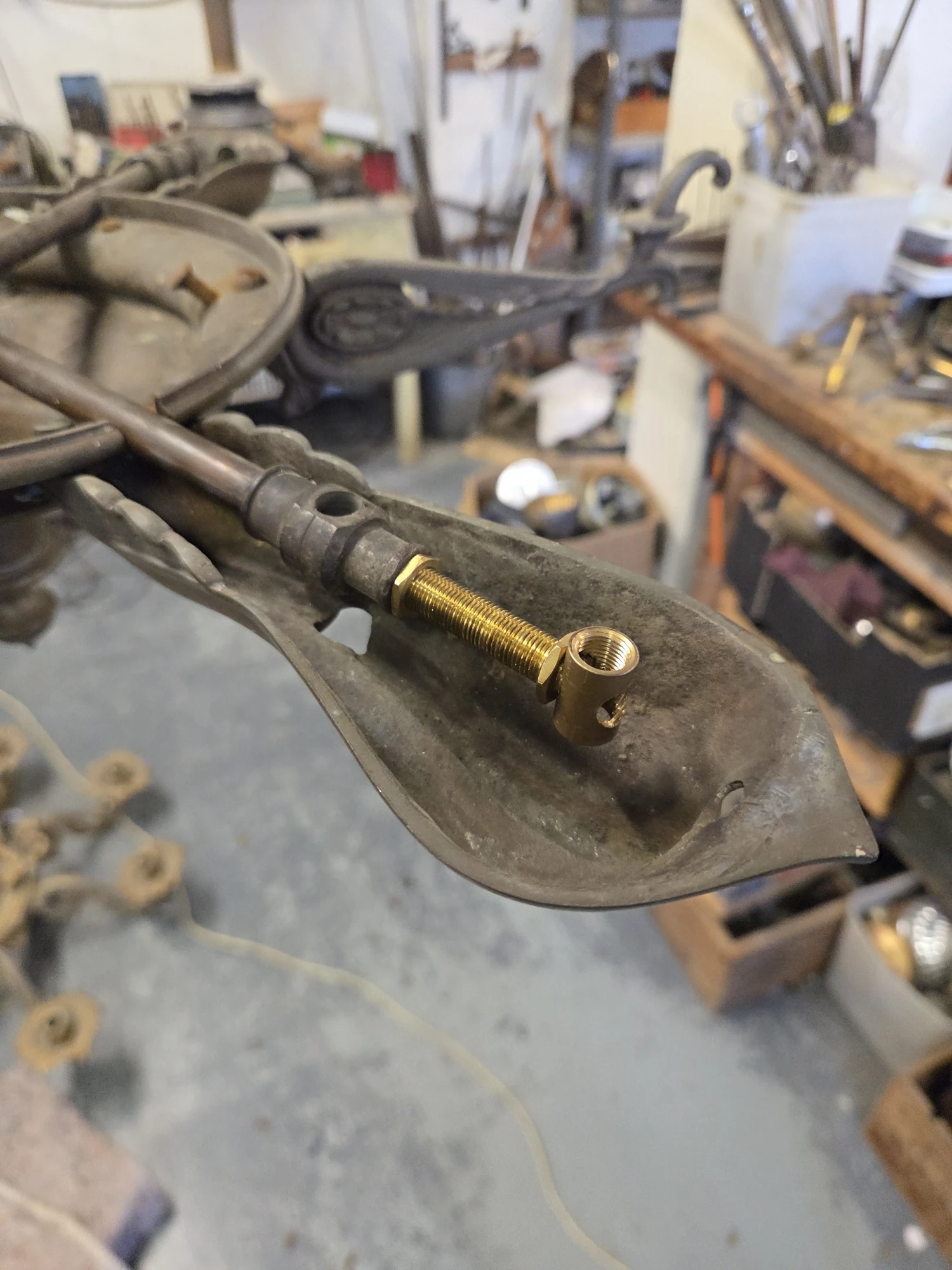 Brass rod and T-shaped coupler fitted to an antique gasolier arm during workshop restoration.