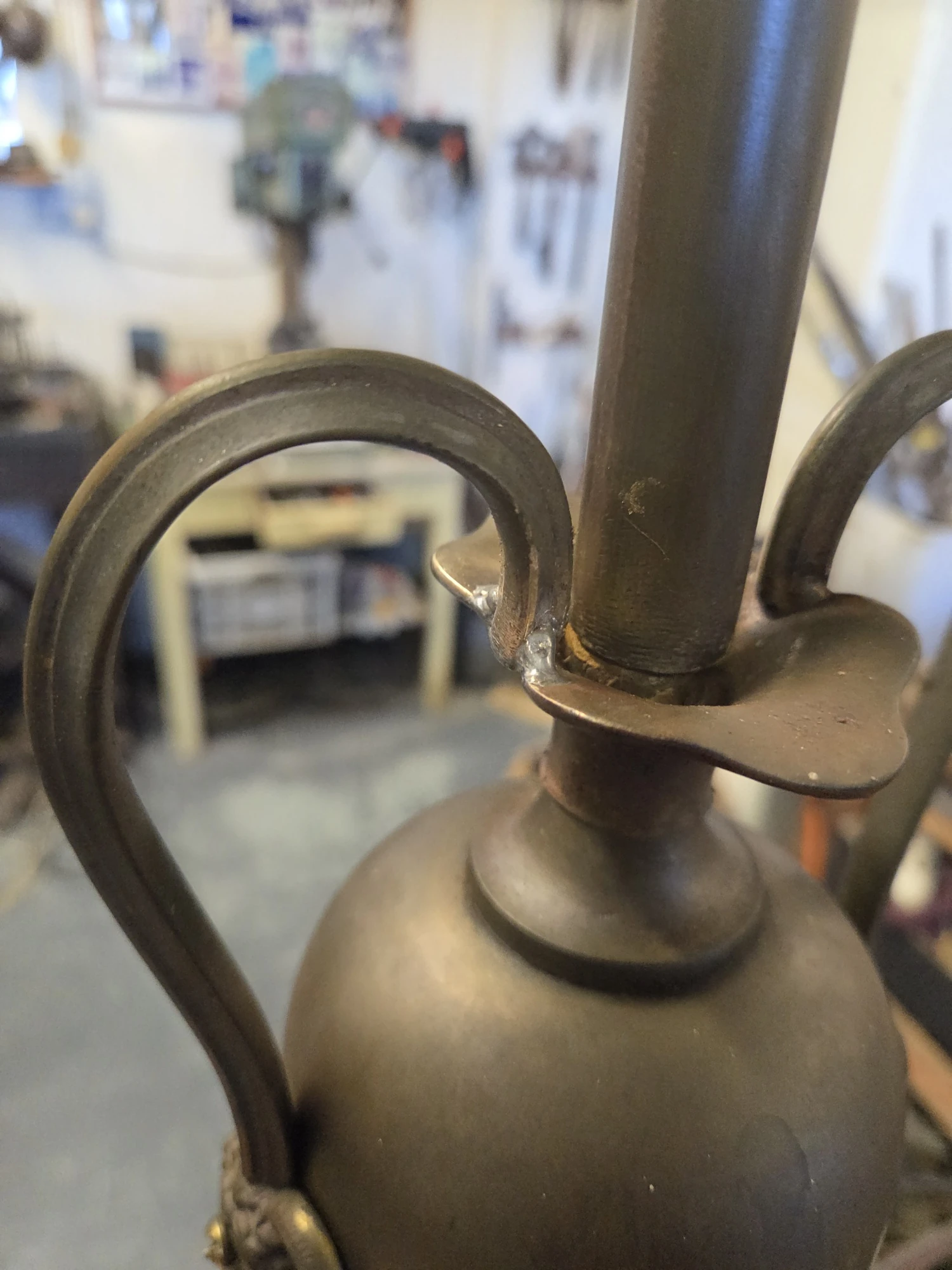 Repaired metal handle on the central urn of an antique gasolier following soft soldering.