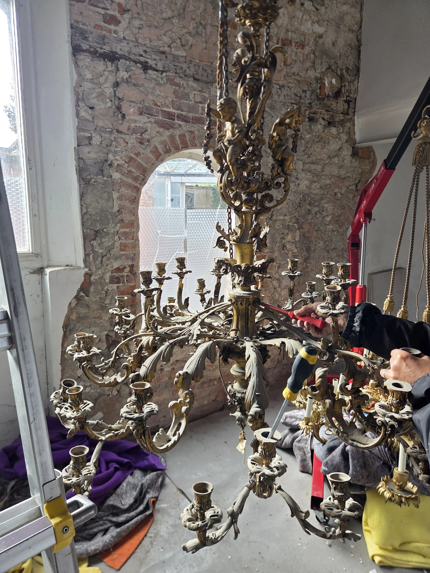 Working on the gilt chandelier at a lower height, with the arms partly removed.