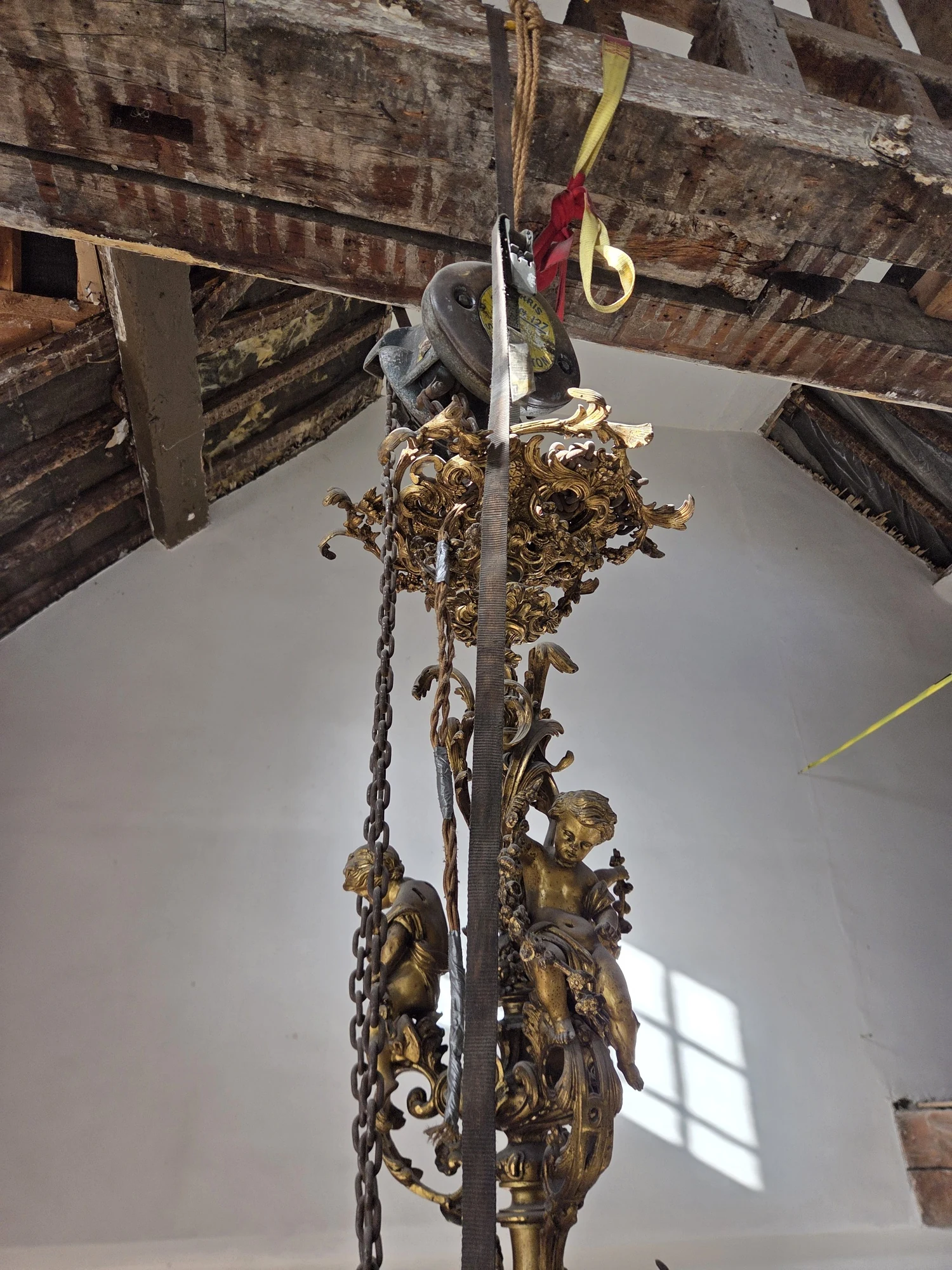 Ornate gilt upper stem of the Rococo chandelier with scrolling decorative metalwork and suspension chains.