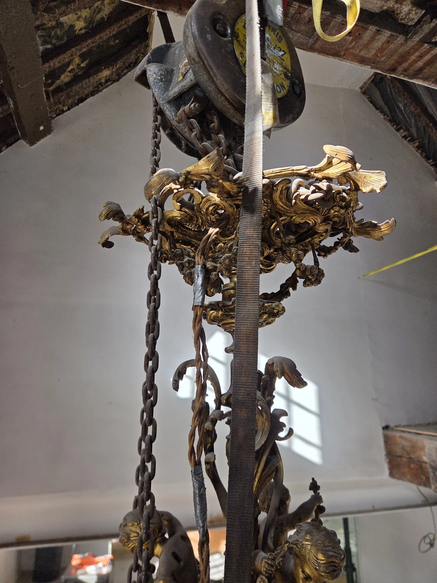 Upper section of the Rococo chandelier with its chains, pulley and existing suspension from the timber beam.