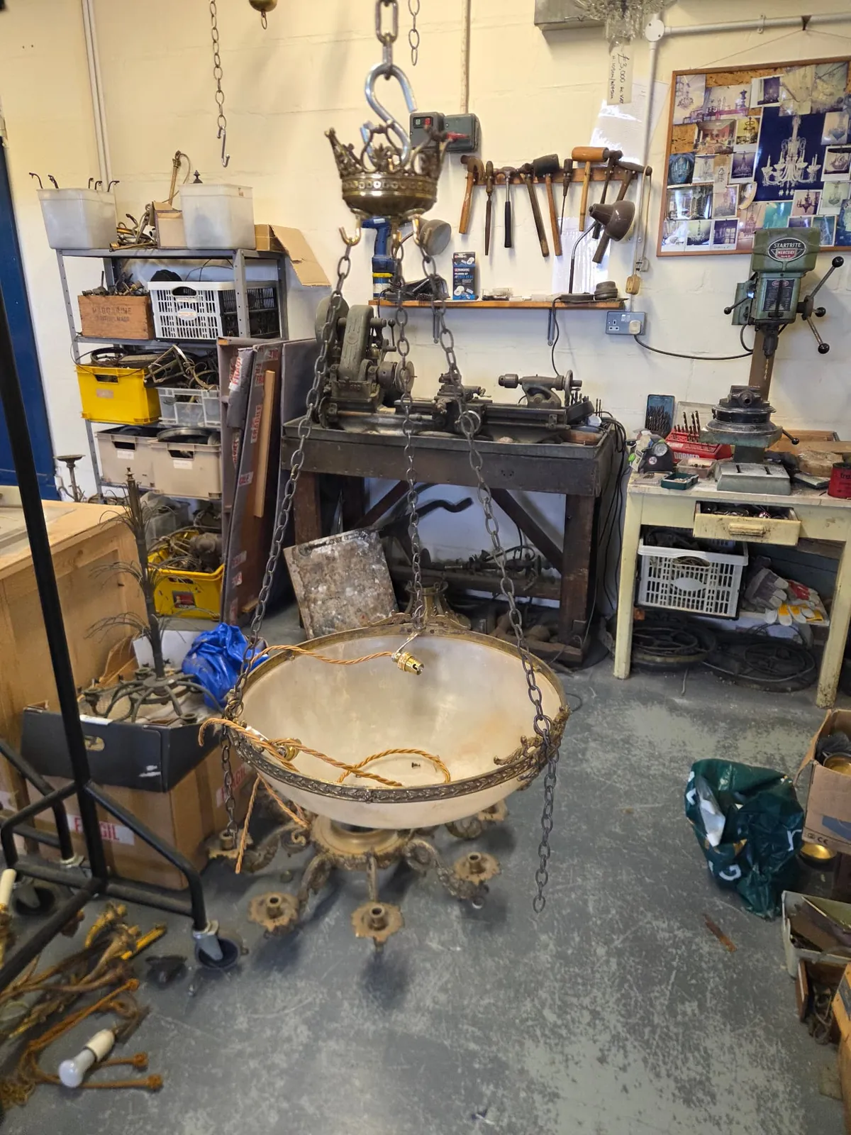 Alabaster bowl chandelier suspended in the G & P Cohn workshop with a new brass light holder and fabric-covered wiring being fitted inside the bowl.