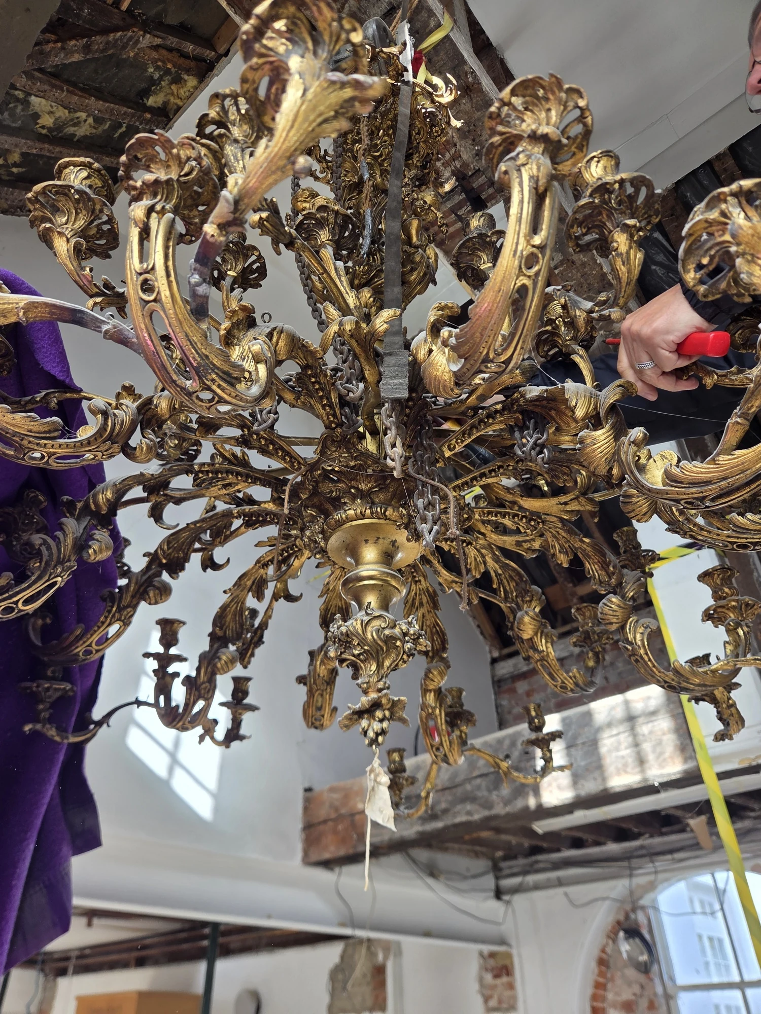 Underside of the Rococo chandelier showing the gilt leaf and scroll metalwork beneath the arms.