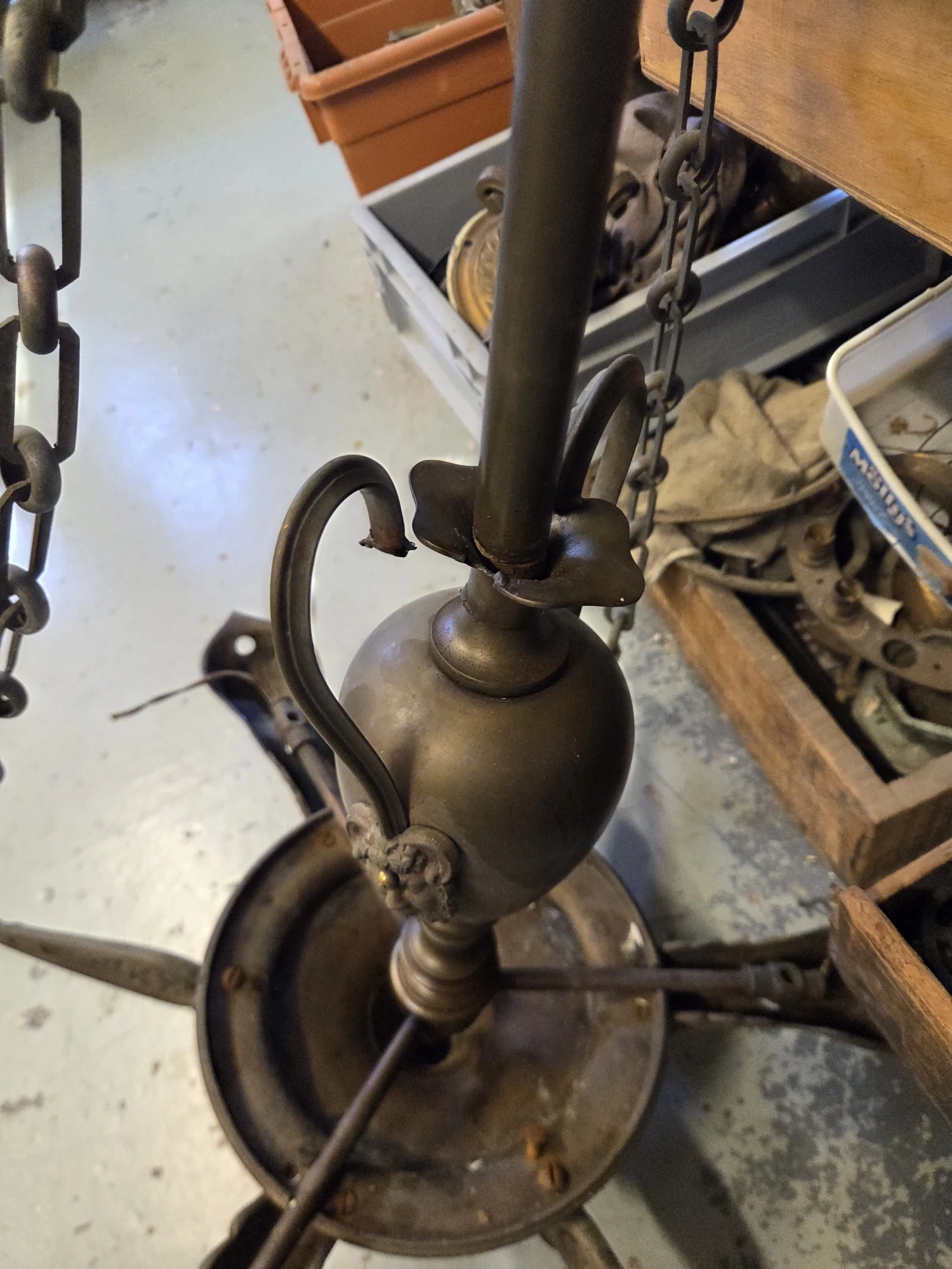 Broken decorative handle on the central urn of an antique gasolier before metal repair.