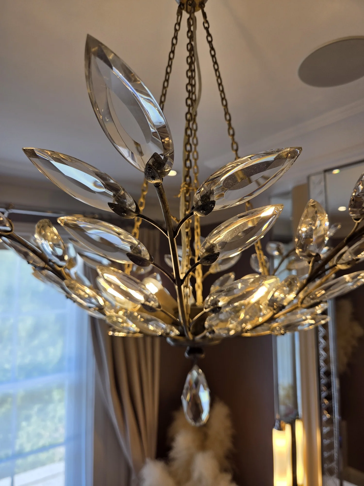 Individually mounted faceted glass leaves on slender metal branches of a chandelier in The Boltons, London.