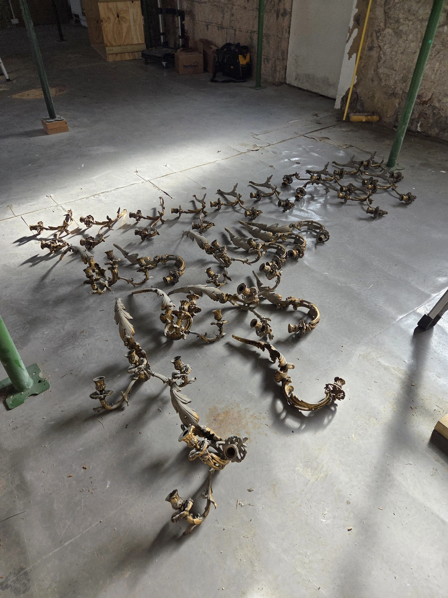 The individually removed gilt chandelier arms laid out on the floor of the outbuilding.