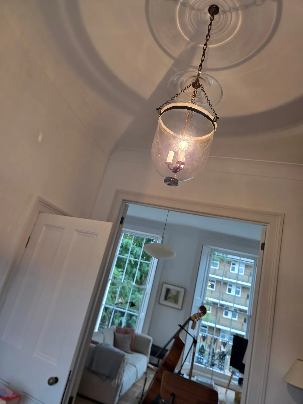 Glass bell lantern illuminated in a hallway of a private residence in Camden, London.