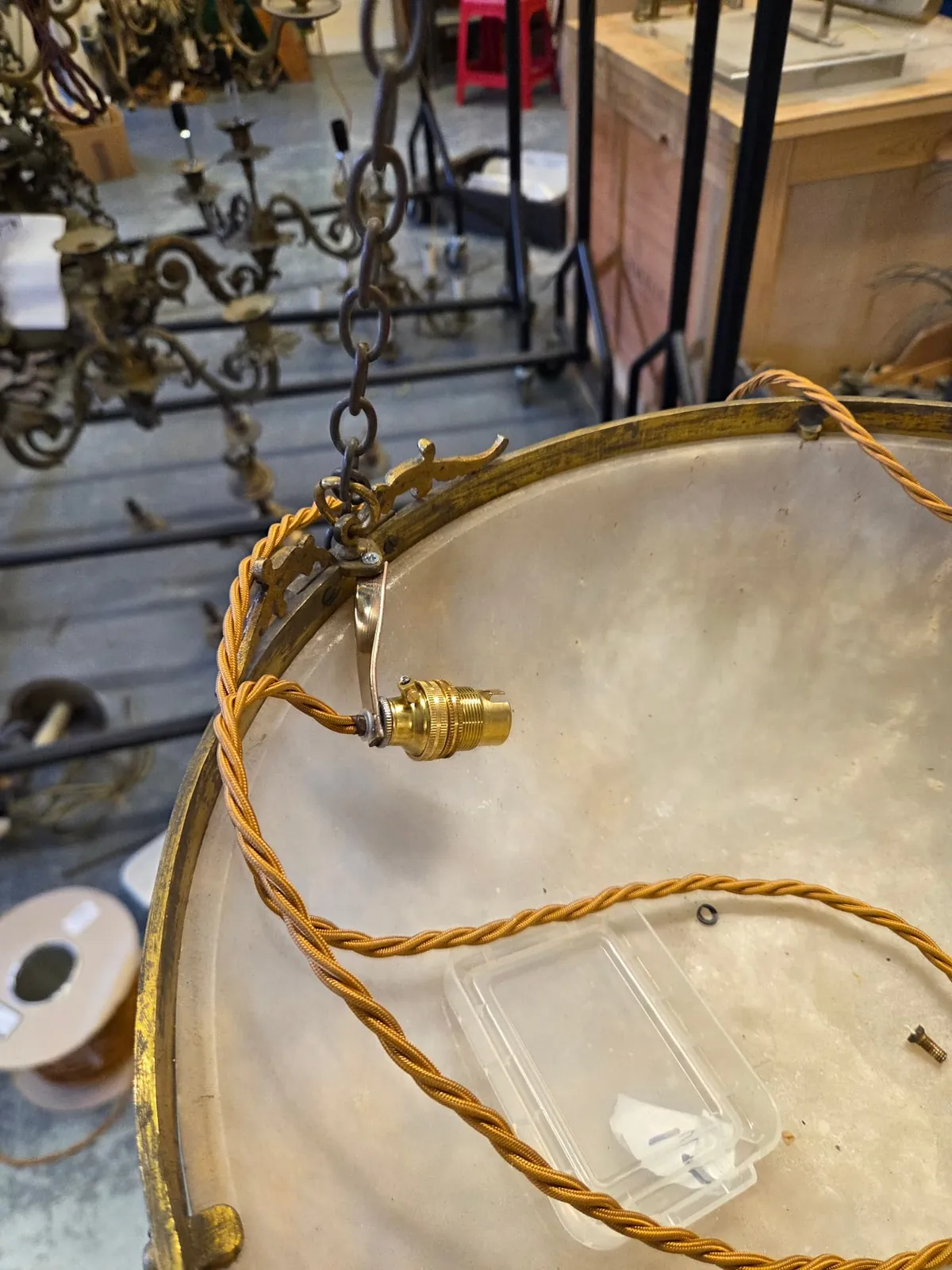 New fabric-covered cable routed along the inside of the decorative rim of an alabaster bowl during electrification in the workshop.