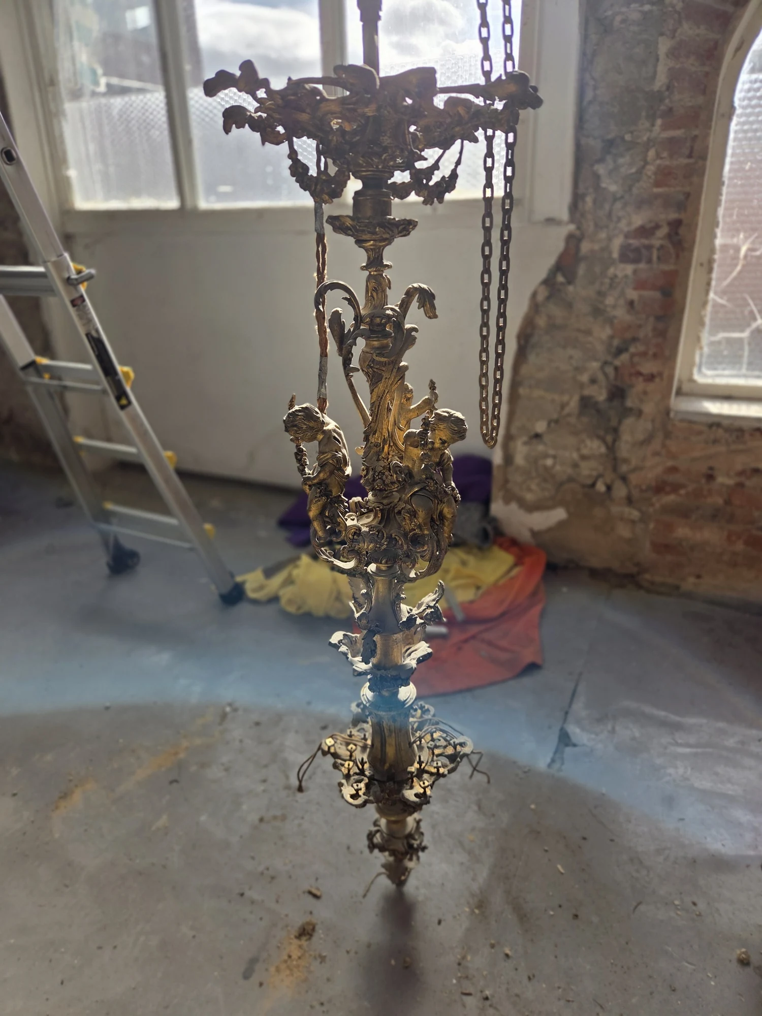 Ornate gilt central stem of the Rococo chandelier, viewed at full height after the arms were removed.