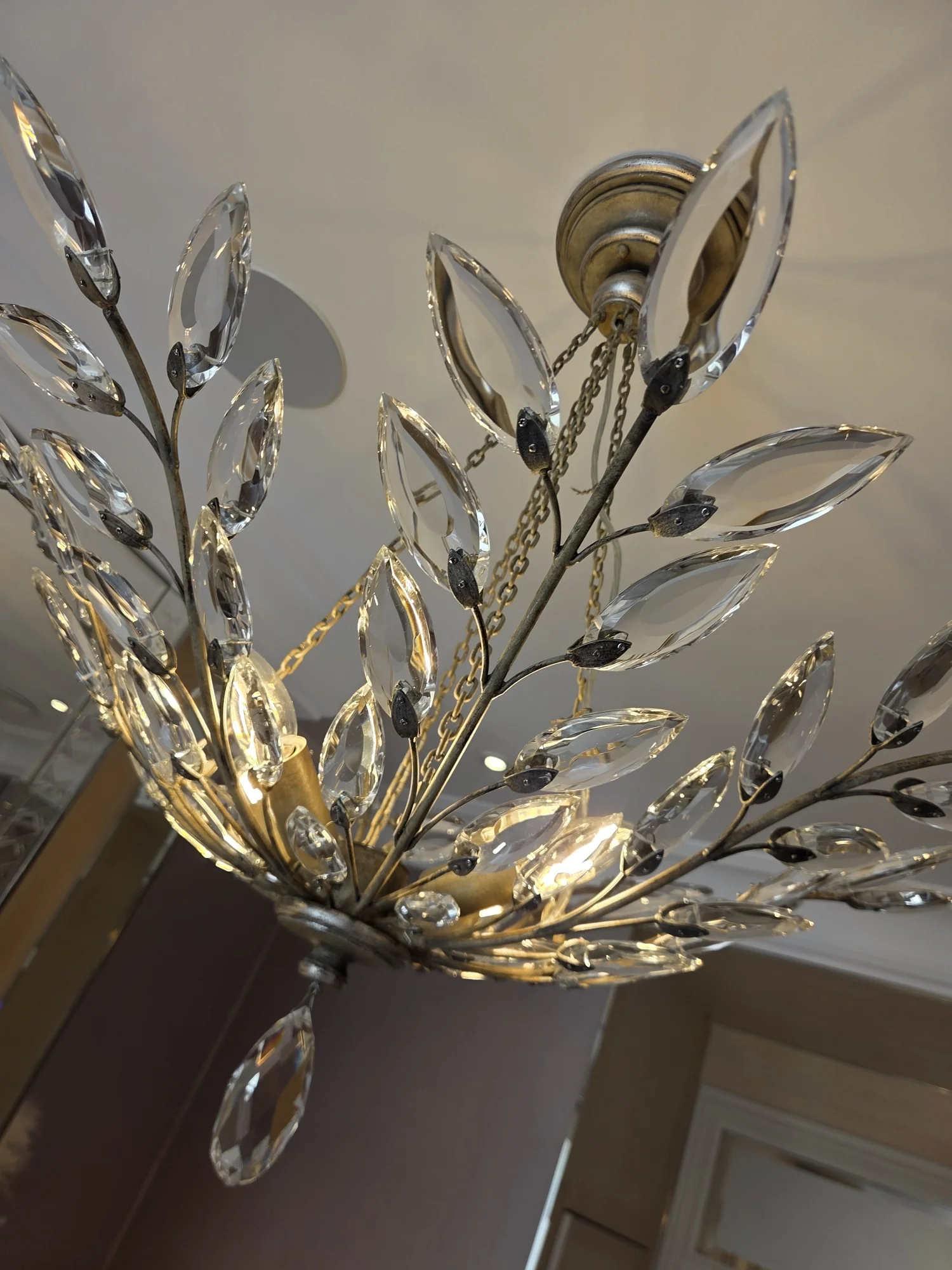 Close view of individual leaf-shaped glass pieces mounted on the branches of a chandelier in The Boltons.