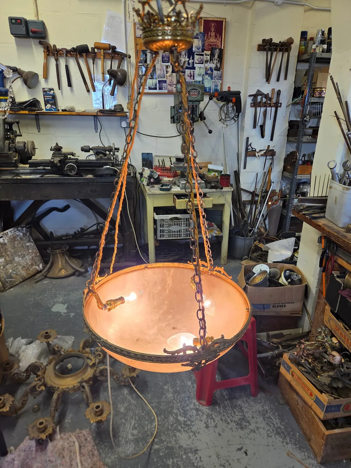 Fully re-electrified alabaster bowl chandelier illuminated in the G & P Cohn workshop, with fabric-covered cable running alongside each suspension chain.