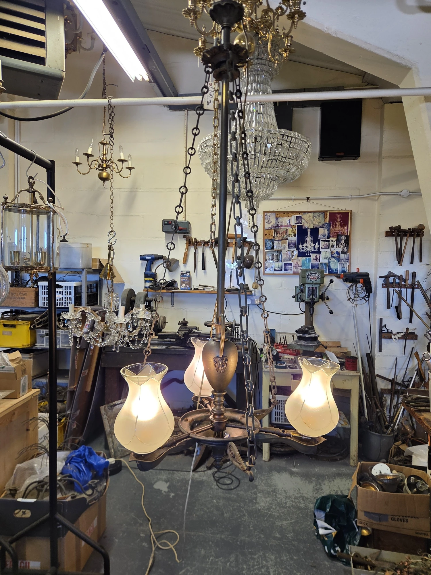 Antique gasolier illuminated after restoration and rewiring, showing its three glowing colza glass shades.
