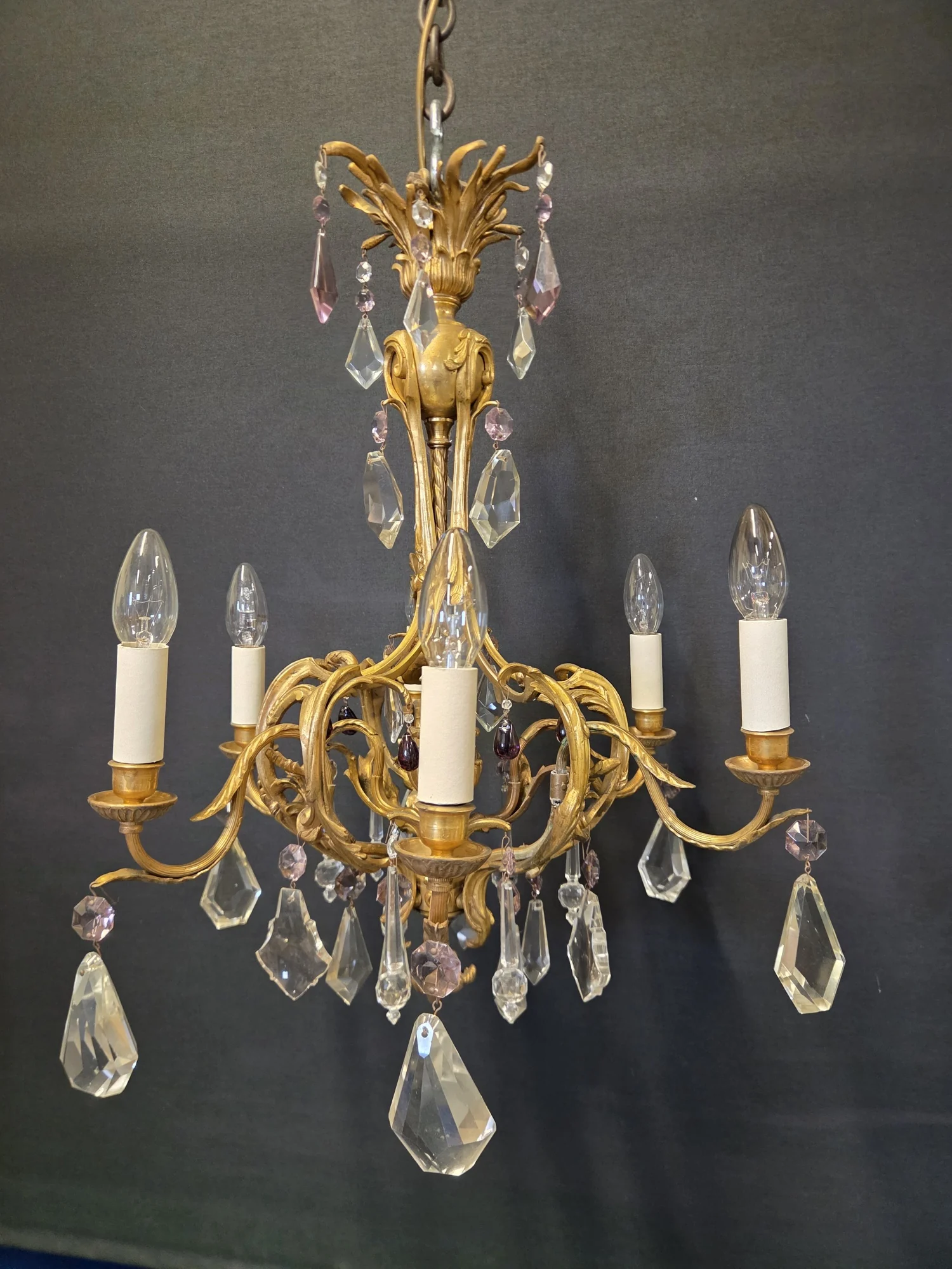 French ormolu six-light chandelier with clear and mauve glass drops, shown in full against a dark background