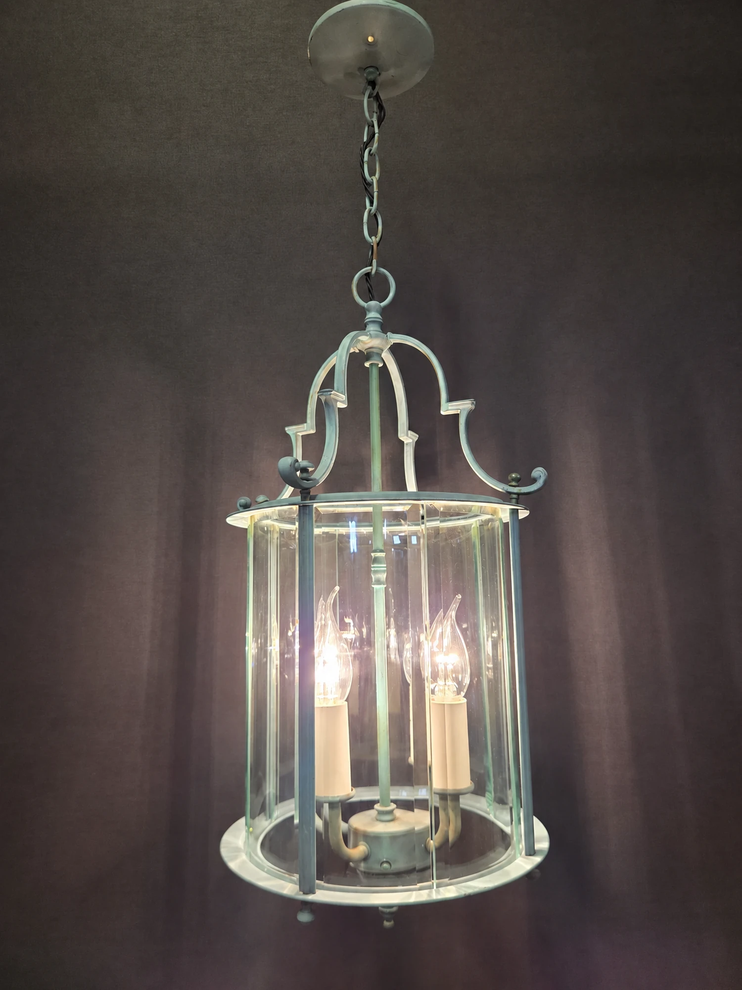 Round green lantern illuminated, shown in full with its four lights lit behind the curved bevelled glass