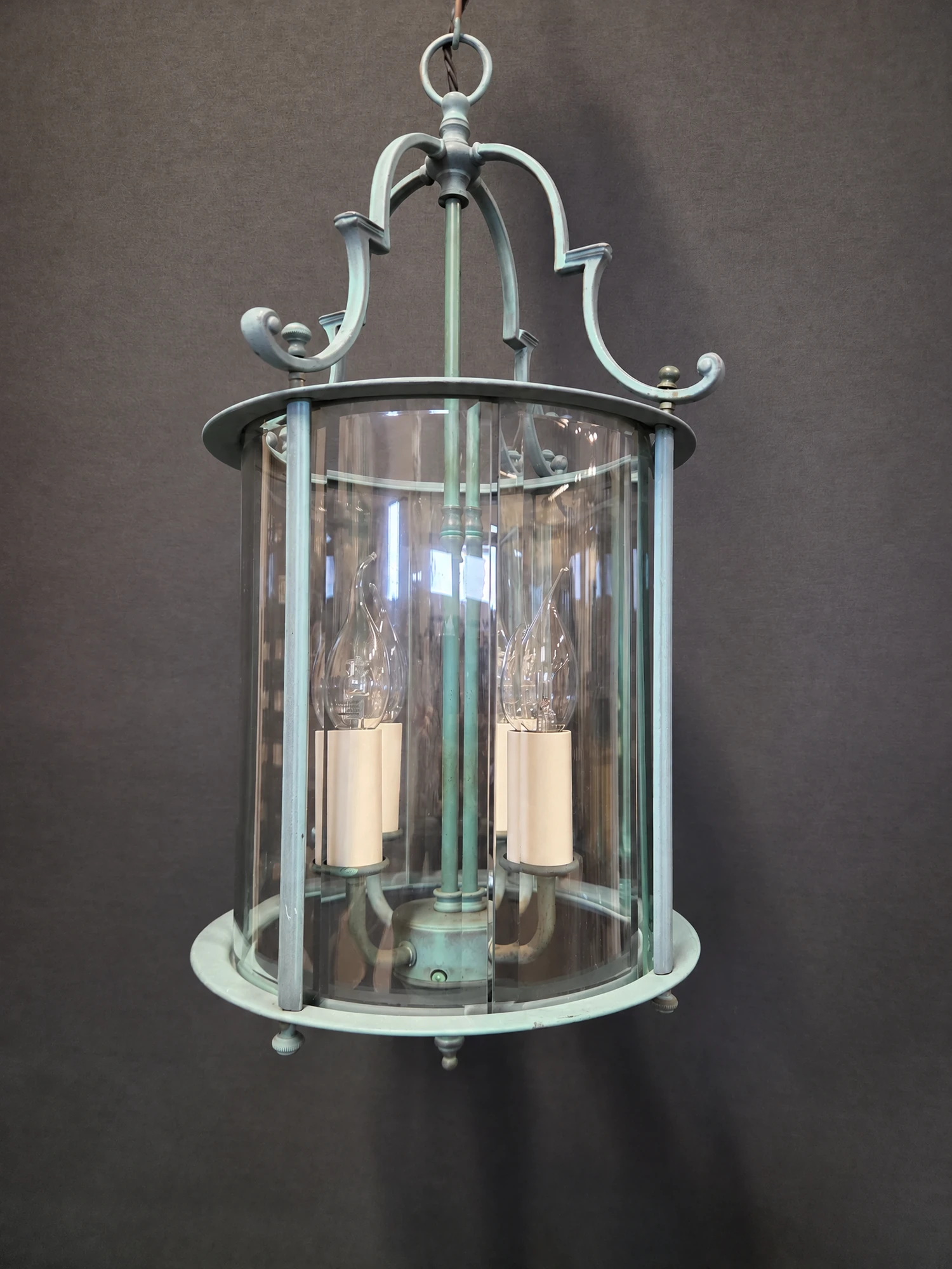 Closer full view of the round green lantern showing the curved bevelled glass panels, scrolled ribs and candle sleeves