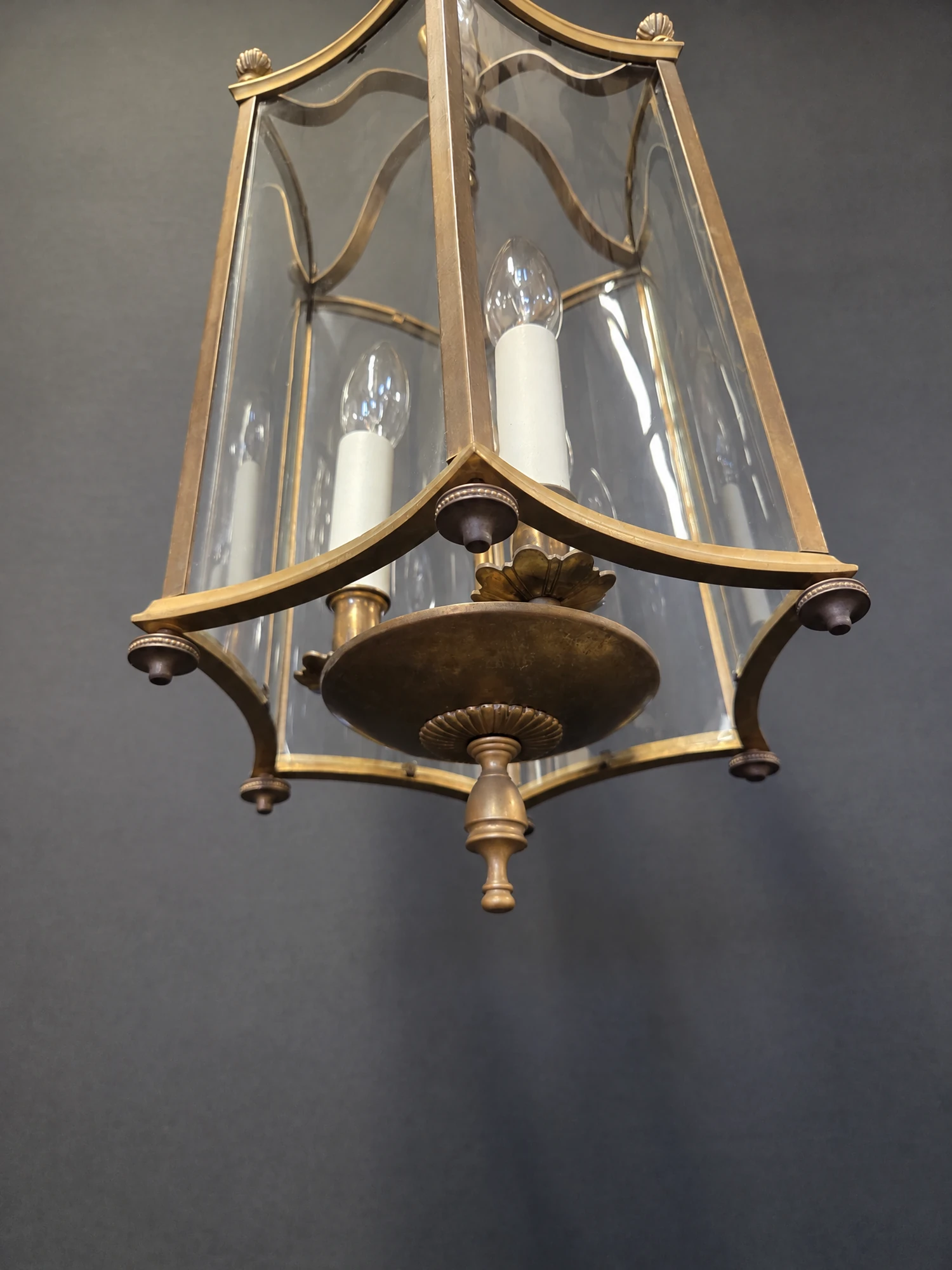 View from below the hexagonal brass lantern showing the base, curved glass panels and candle sleeves
