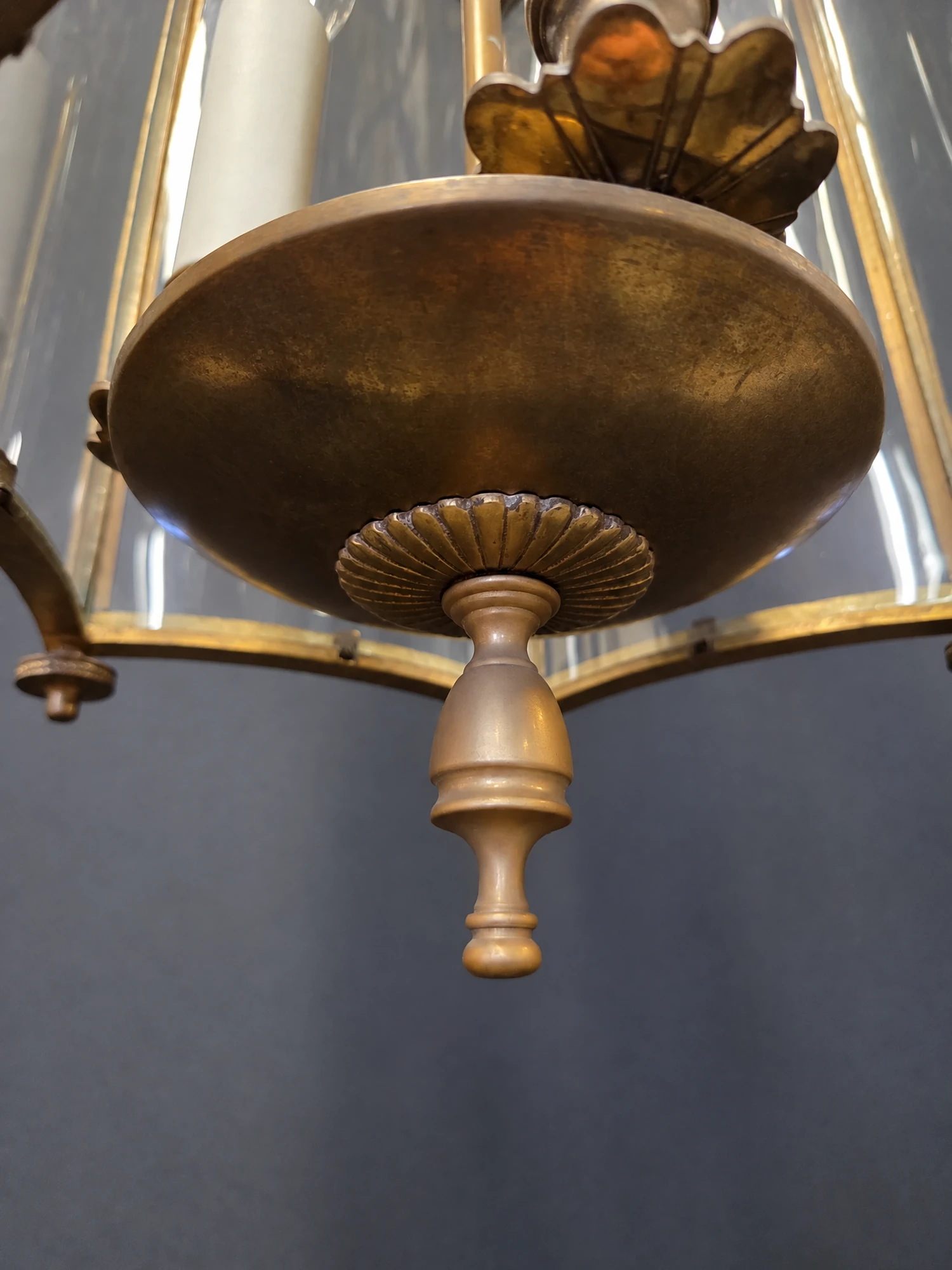 Close-up of the brass base dish and turned drop finial beneath the lantern