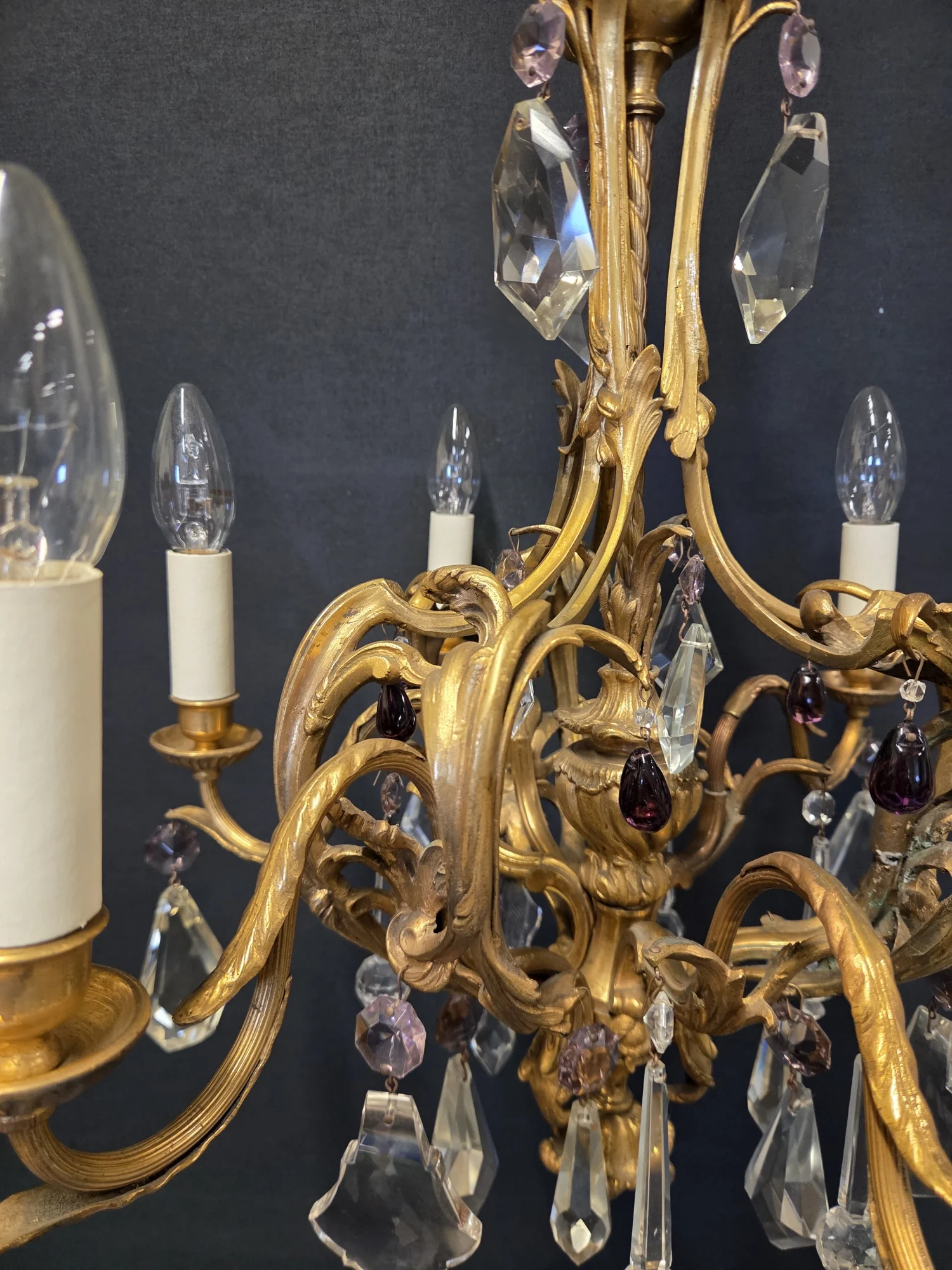 Close-up of the scrolling ormolu arms with purple pear drops and clear glass