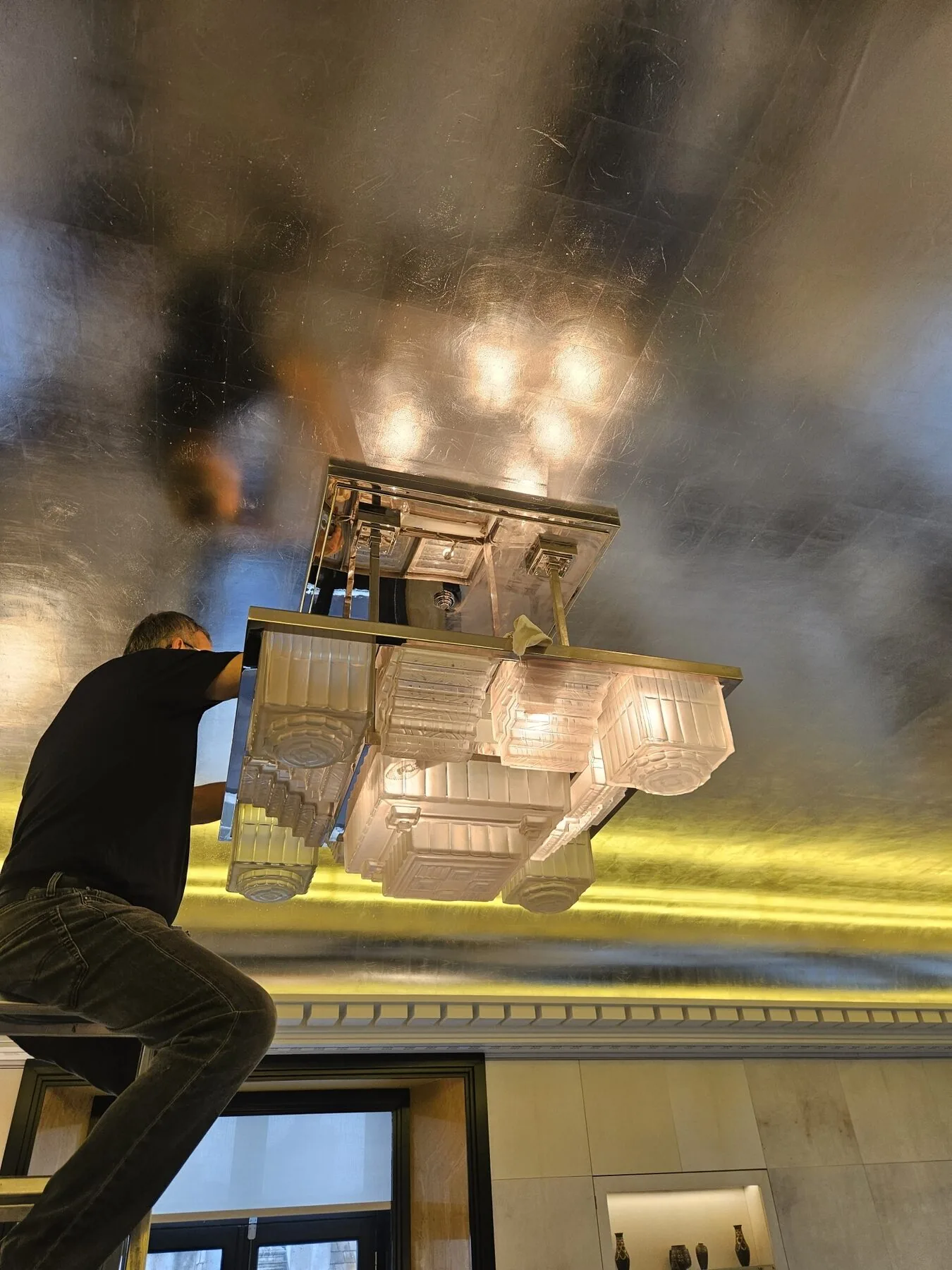 Cleaning in progress from below, showing the nickel-plated frame and stepped glass shades