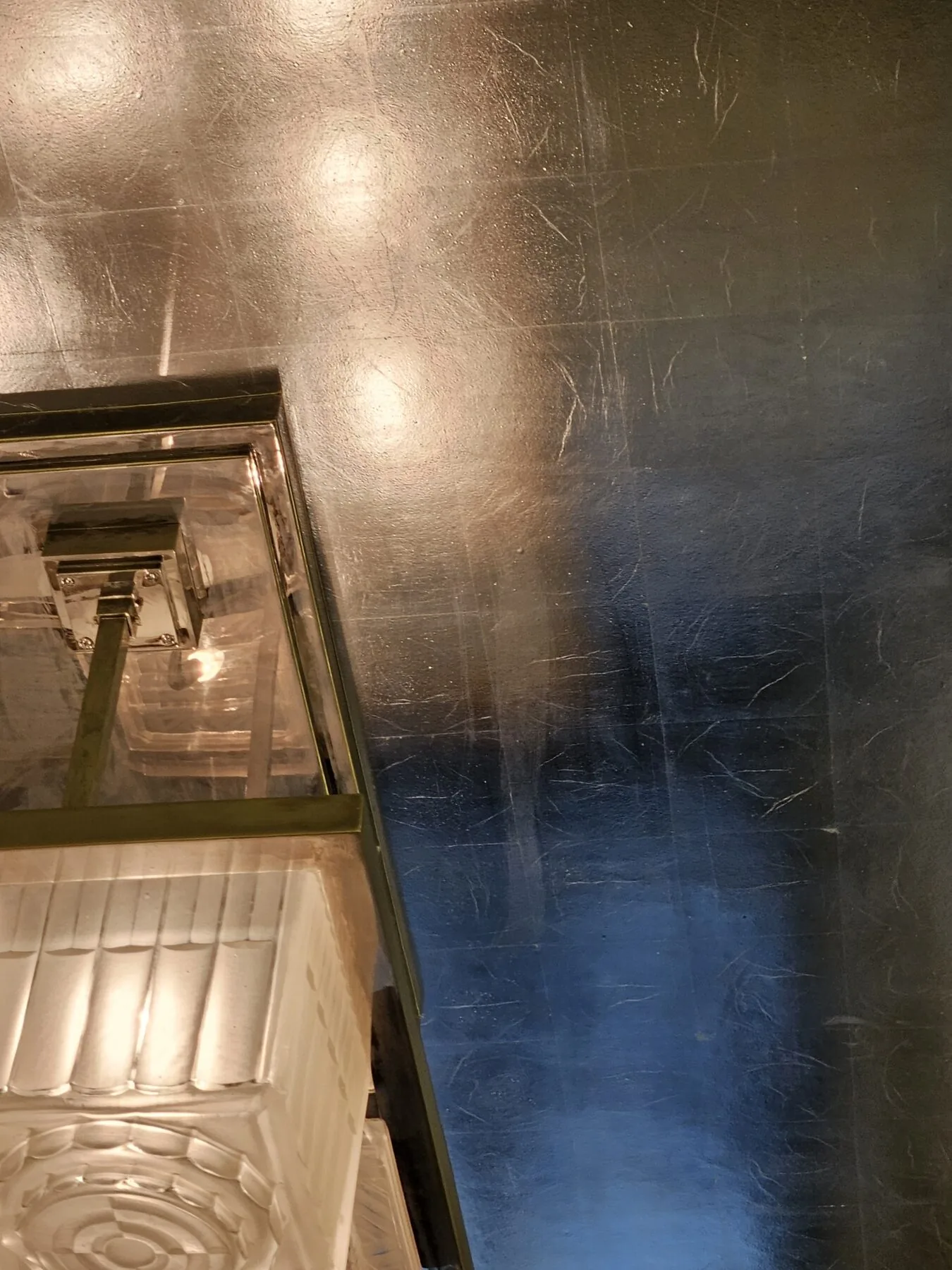Detail of the nickel-plated frame against the silvered ceiling