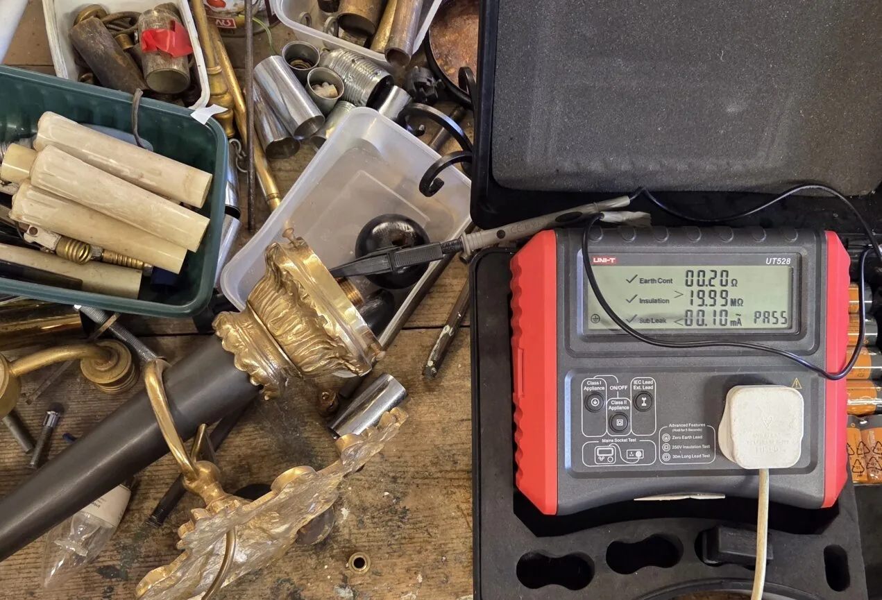 PAT testing equipment alongside antique chandelier components in workshop