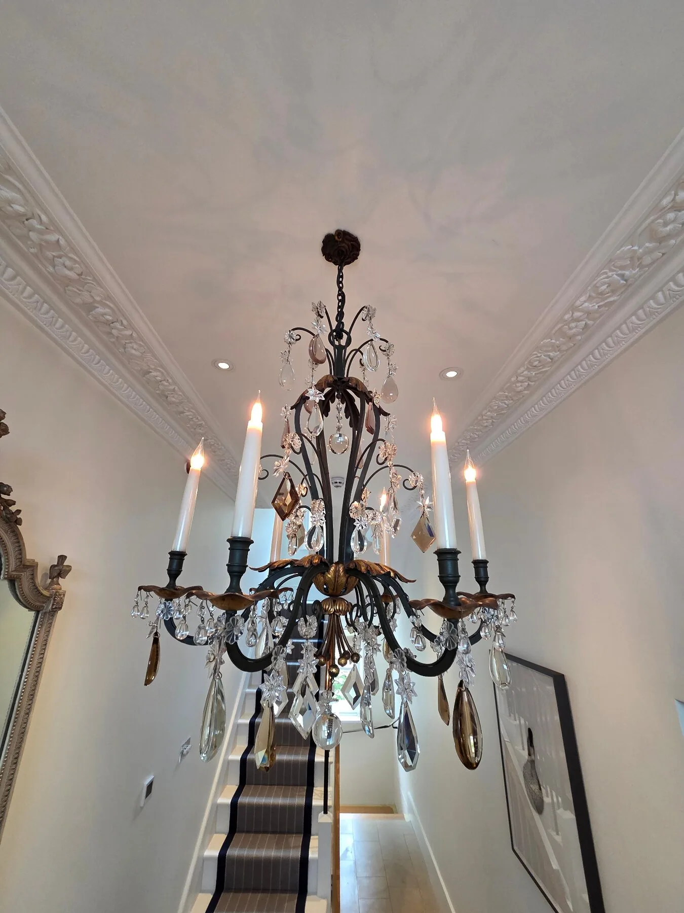 Wrought iron and crystal chandelier suspended in the Holland Park stairwell after cleaning