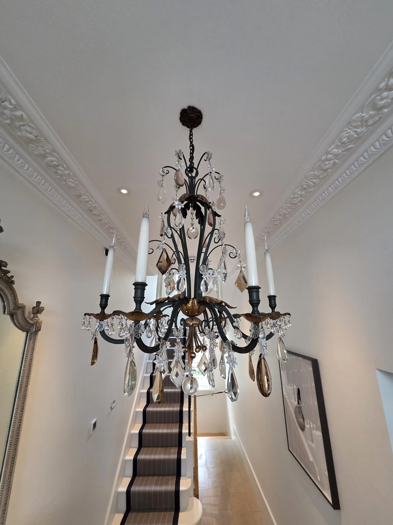 Full view of the six-arm chandelier lit above the staircase following in-situ cleaning