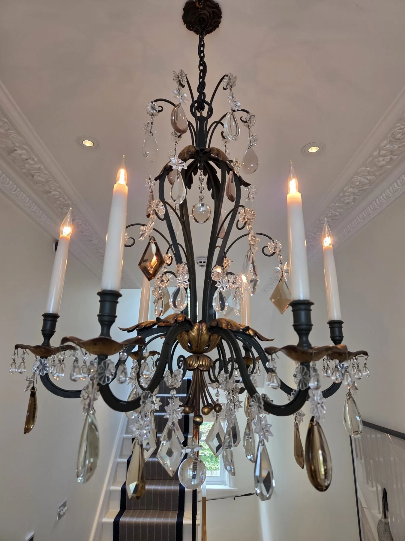 The chandelier illuminated, showing the restored clarity of its cut crystal drops