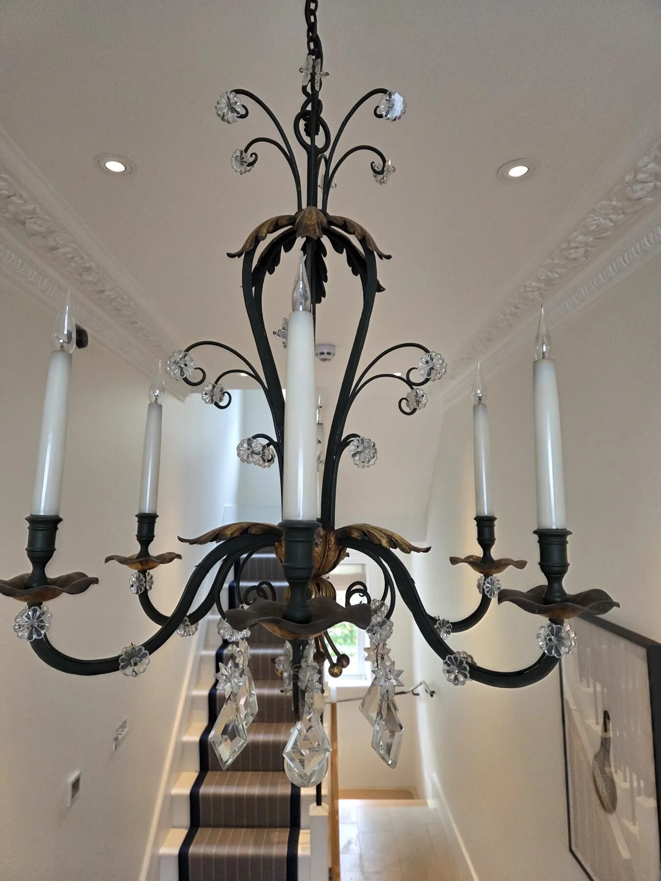 Side view of the chandelier showing the scrolled arms and gilt drip pans