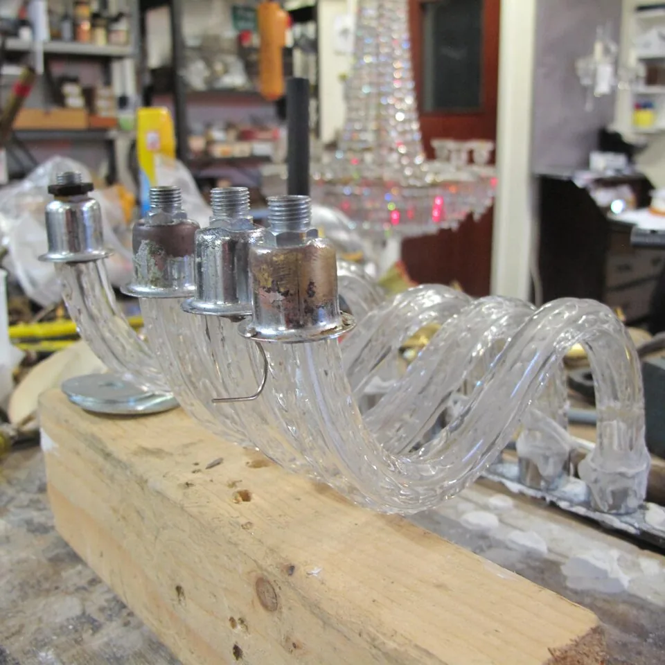 Workshop bench with glass chandelier arms being set into metal fittings