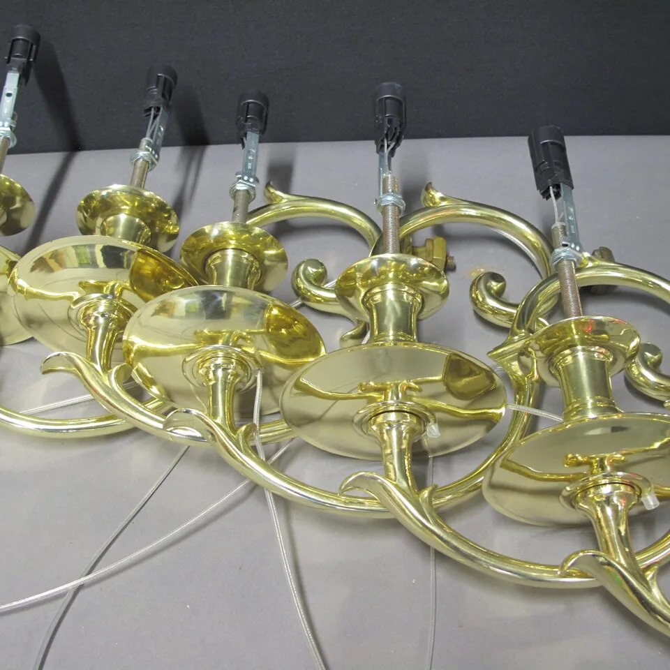Polished brass chandelier arms lined up in the workshop