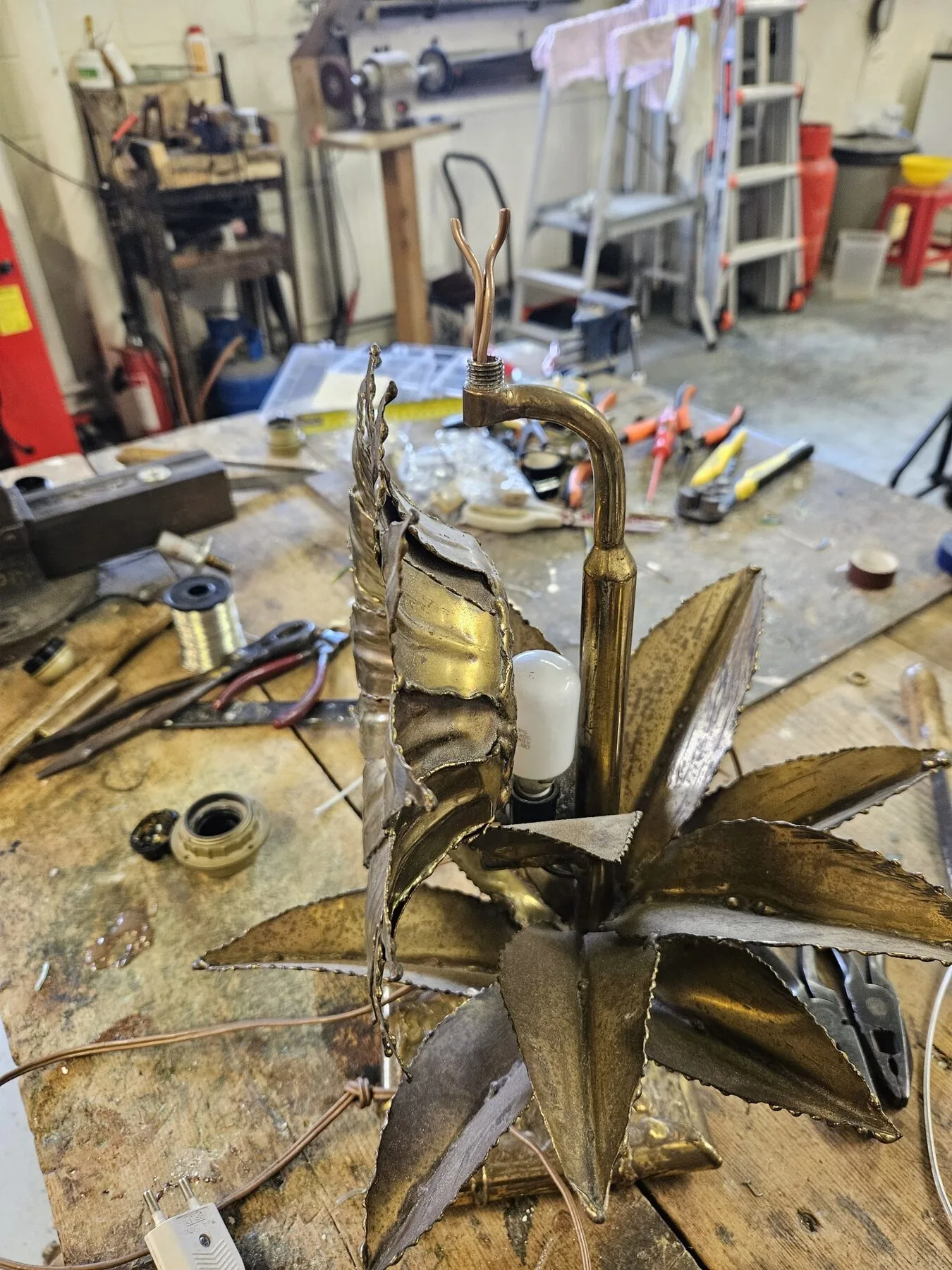 Sunflower lamp on the workbench with wiring exposed at the top of the stem