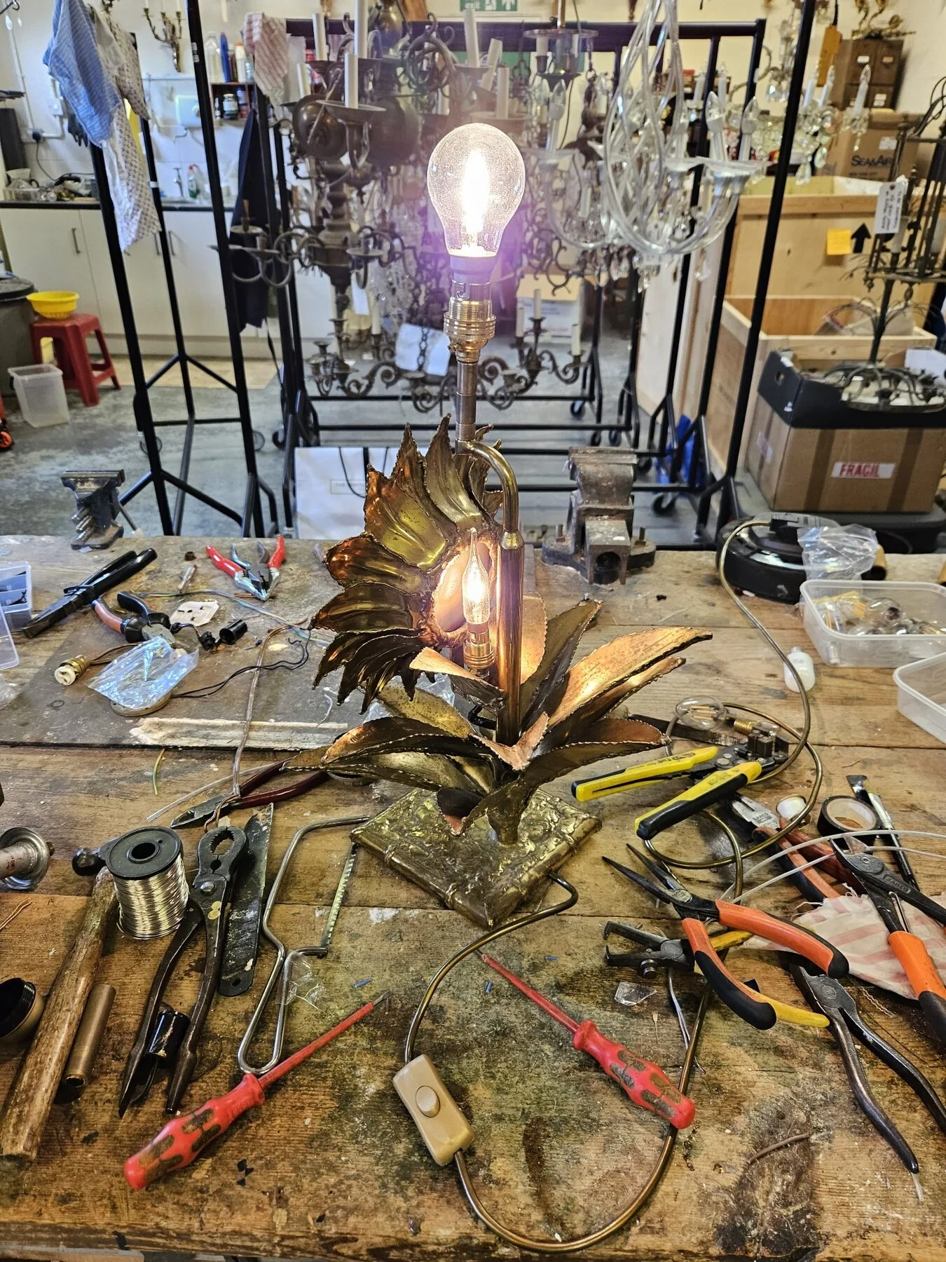 Sunflower lamp fully reassembled and lit on the workbench after re-electrification