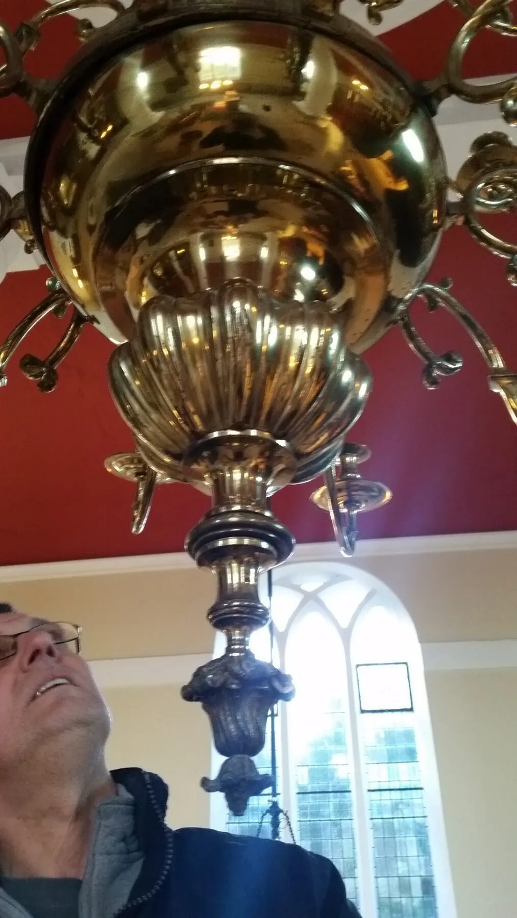 Detail of the polished brass bowl and shell-form receiver of the church chandelier